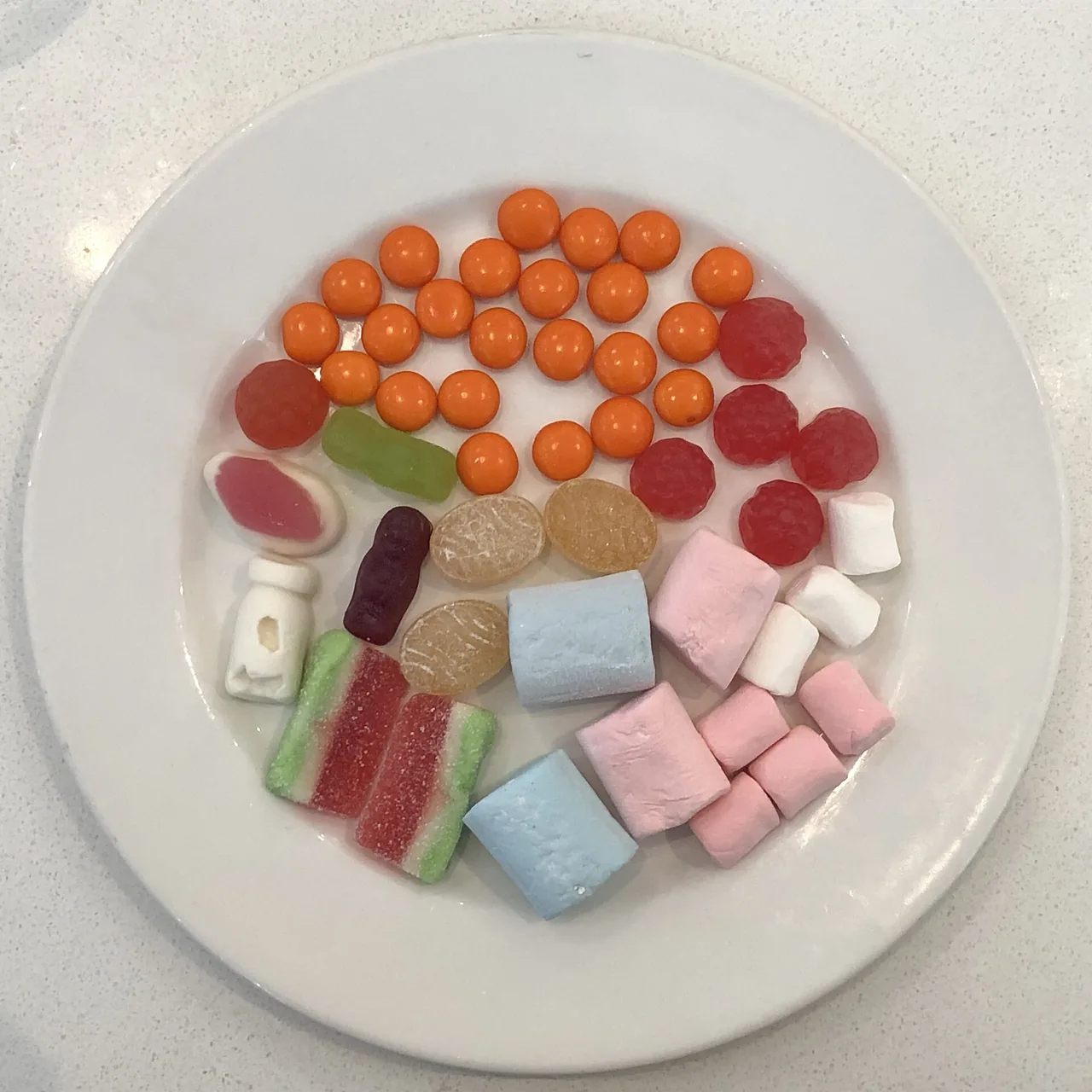 Beyaz tabakta renkli şekerler, jelibonlar ve marshmallowlar